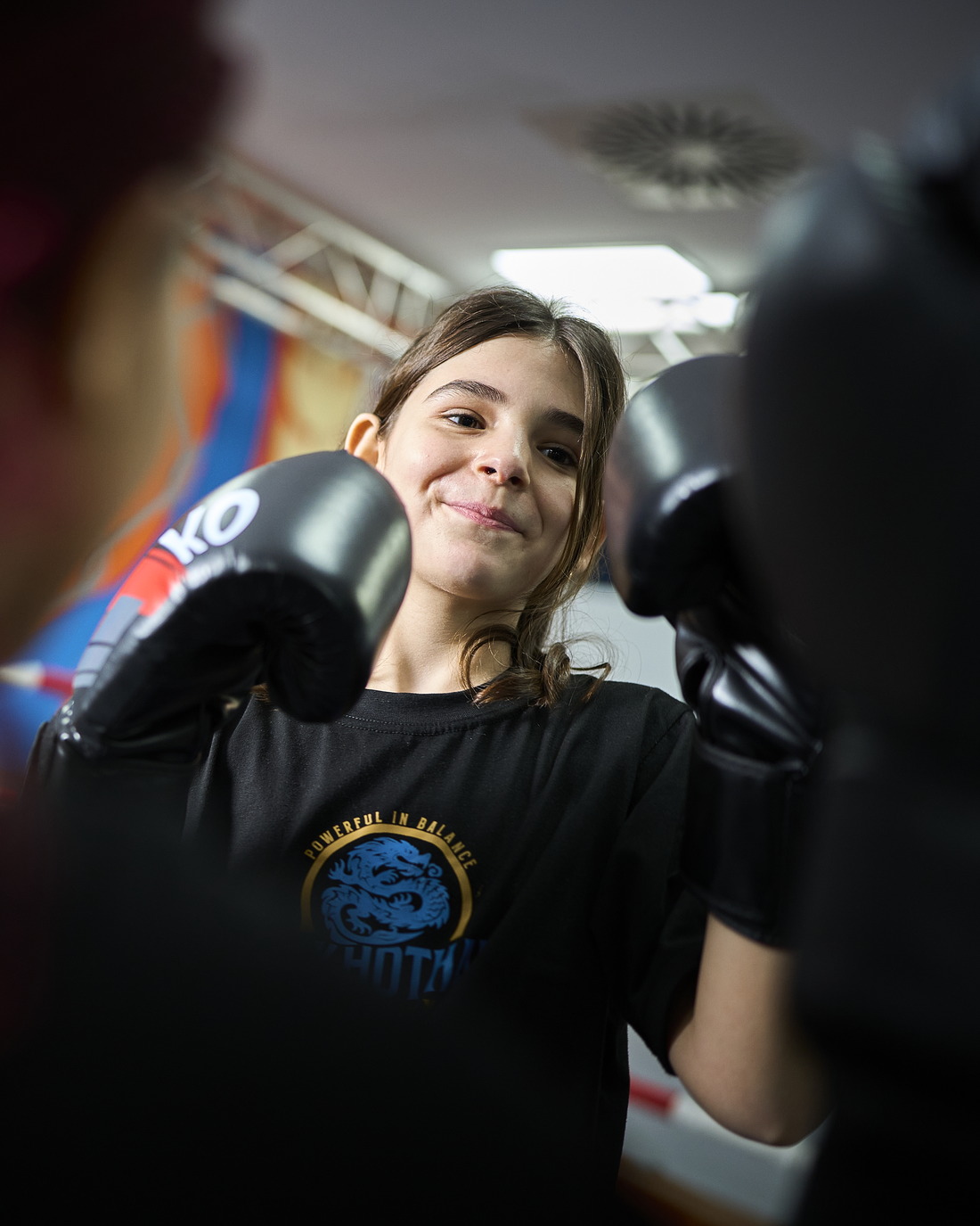 Ein Mädchen im Teenager-Alter lächelt beim Training mit Boxhandschuhen.